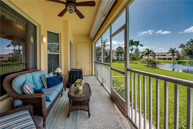 sunroom with ceiling fan and a water view