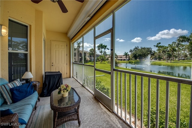 sunroom featuring ceiling fan and a water view