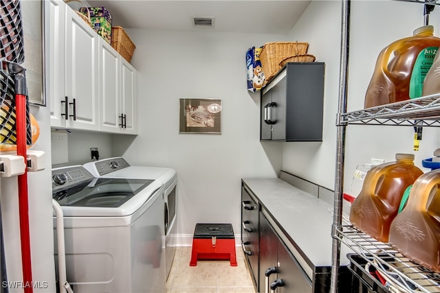 washroom featuring cabinets, light tile patterned floors, and washer and clothes dryer