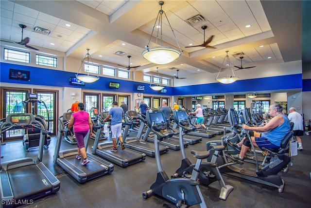 gym featuring a towering ceiling, ceiling fan, and coffered ceiling