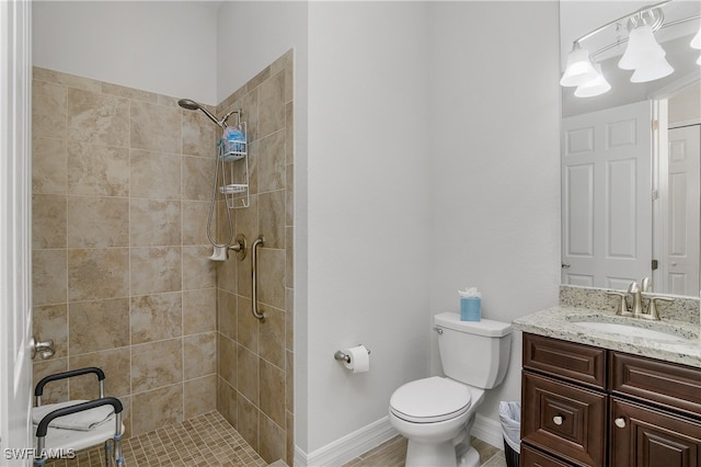 bathroom featuring a tile shower, vanity, and toilet