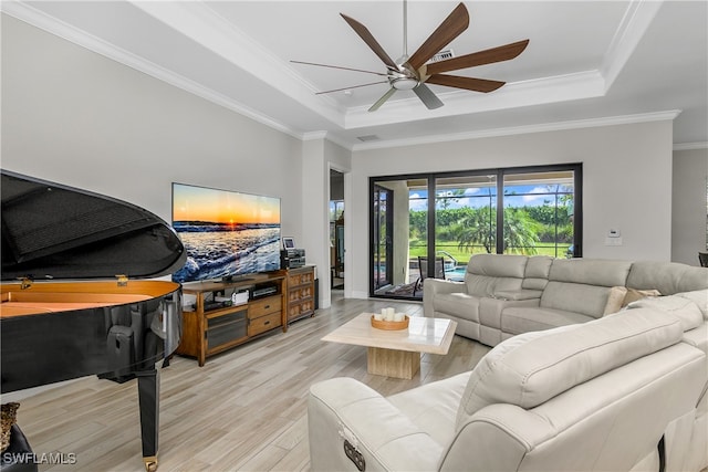 living room with ornamental molding, light hardwood / wood-style floors, ceiling fan, and a tray ceiling