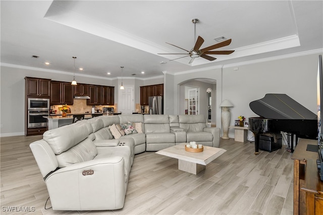 living room with ceiling fan, light hardwood / wood-style floors, crown molding, and a tray ceiling