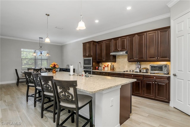 kitchen with stainless steel appliances, crown molding, light hardwood / wood-style floors, a kitchen bar, and a kitchen island with sink