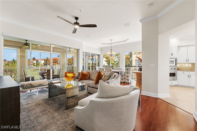 living room with ceiling fan with notable chandelier, light wood-type flooring, and crown molding