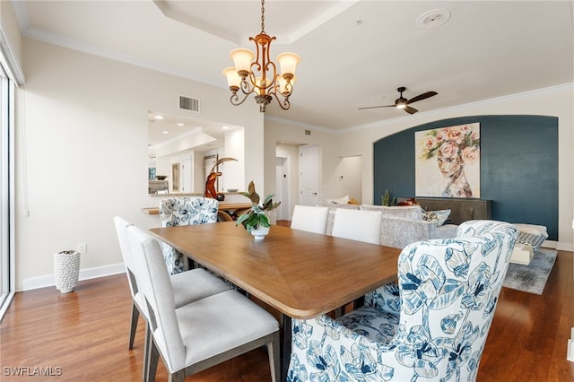 dining room featuring ornamental molding, wood-type flooring, a tray ceiling, and ceiling fan with notable chandelier