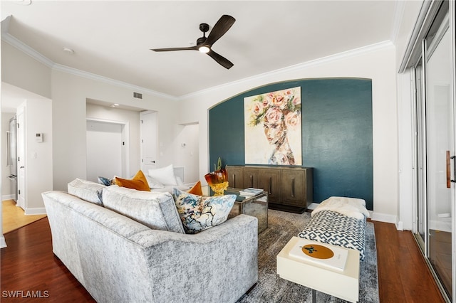 living room with ornamental molding, ceiling fan, and dark wood-type flooring