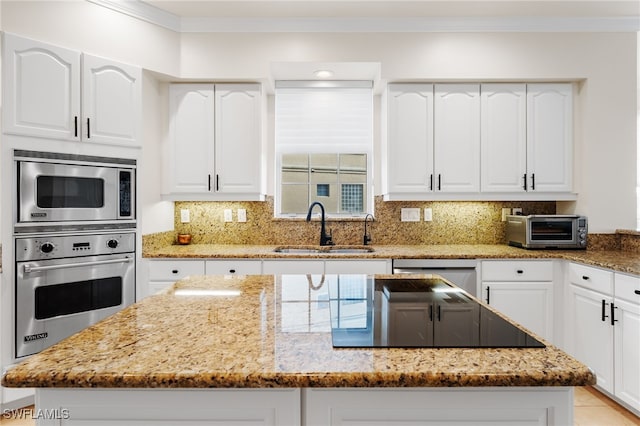 kitchen with sink, stainless steel appliances, light stone counters, decorative backsplash, and white cabinets