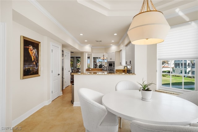 dining room featuring a raised ceiling, plenty of natural light, and ornamental molding