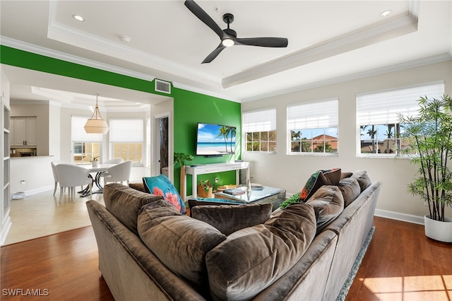 living room featuring dark hardwood / wood-style flooring, a tray ceiling, and ceiling fan