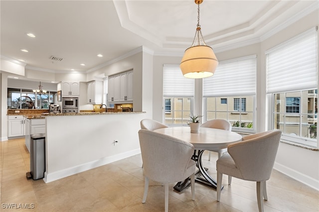 dining area with crown molding, light tile patterned floors, sink, and a tray ceiling