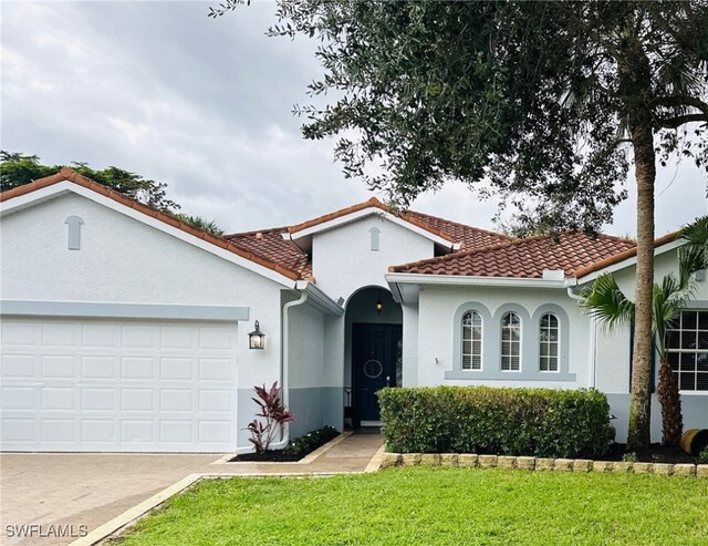 mediterranean / spanish home featuring a front lawn and a garage