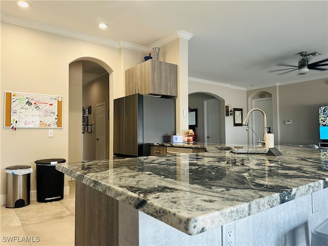 kitchen featuring ceiling fan, light tile patterned floors, ornamental molding, kitchen peninsula, and stainless steel refrigerator