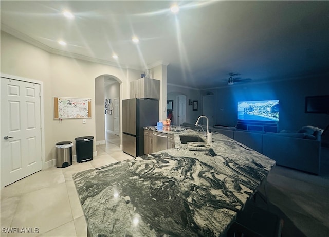 kitchen with light tile patterned floors, ornamental molding, sink, stone counters, and stainless steel appliances