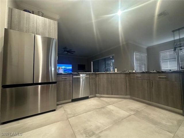 kitchen with dark brown cabinetry, crown molding, stainless steel appliances, and dark stone counters