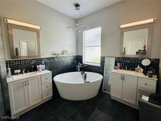 bathroom with a bathing tub, tile patterned floors, a notable chandelier, tile walls, and vanity