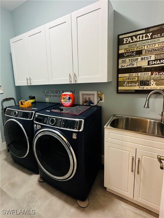 laundry room featuring washing machine and dryer, sink, and cabinets