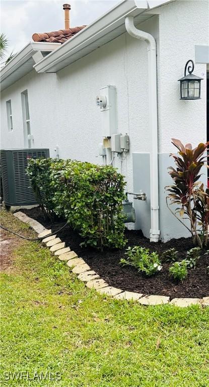 view of side of property featuring a yard and central AC