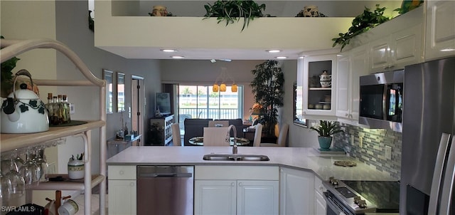 kitchen featuring stainless steel appliances, kitchen peninsula, sink, and white cabinetry