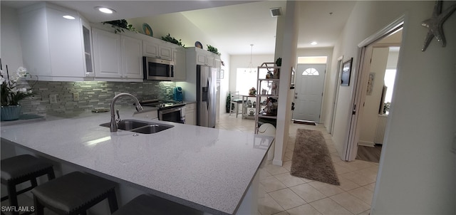 kitchen featuring sink, kitchen peninsula, white cabinetry, stainless steel appliances, and a kitchen breakfast bar