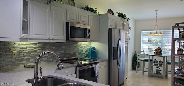 kitchen featuring white cabinets, stainless steel appliances, tasteful backsplash, and decorative light fixtures