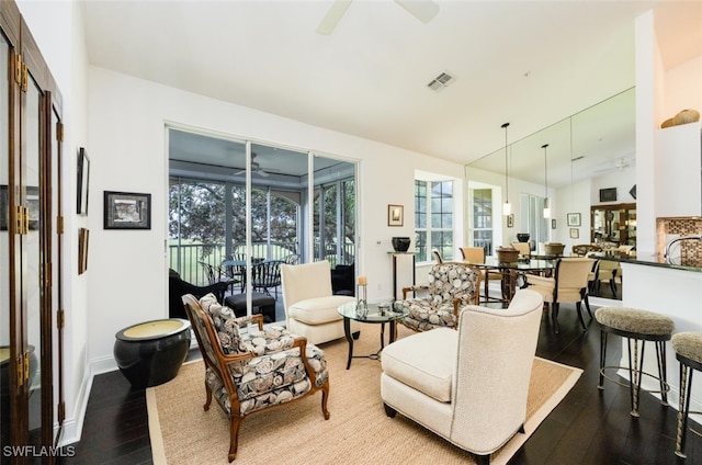 living room with a sunroom, ceiling fan, visible vents, and wood finished floors