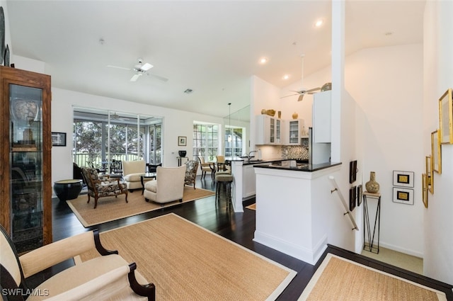 dining space with baseboards, high vaulted ceiling, dark wood-style flooring, and a ceiling fan