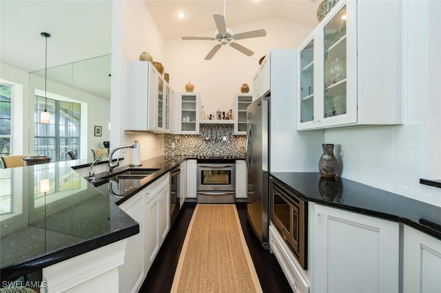 kitchen featuring stainless steel appliances, a sink, white cabinets, hanging light fixtures, and decorative backsplash