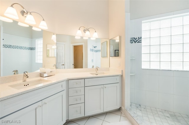 full bathroom featuring double vanity, tiled shower, tile patterned flooring, and a sink