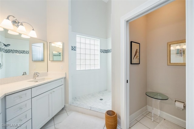 bathroom with baseboards, tiled shower, vanity, and tile patterned floors