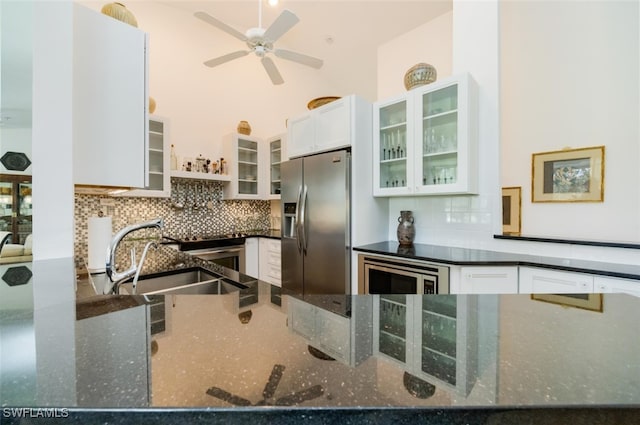 kitchen featuring appliances with stainless steel finishes, dark stone counters, a sink, and decorative backsplash