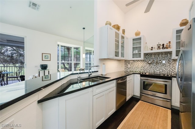 kitchen featuring white cabinets, appliances with stainless steel finishes, decorative backsplash, and a sink