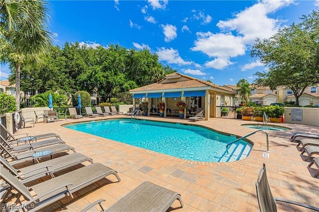 community pool featuring a hot tub, fence, and a patio