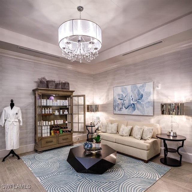 living area with visible vents, ornamental molding, a notable chandelier, and wood finished floors