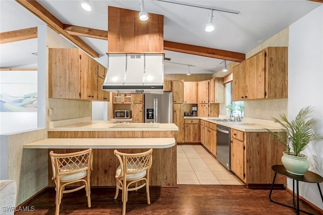 kitchen with lofted ceiling with beams, hanging light fixtures, light wood-type flooring, kitchen peninsula, and stainless steel appliances