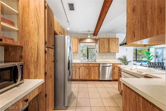 kitchen featuring beam ceiling, sink, tasteful backsplash, light tile patterned floors, and appliances with stainless steel finishes