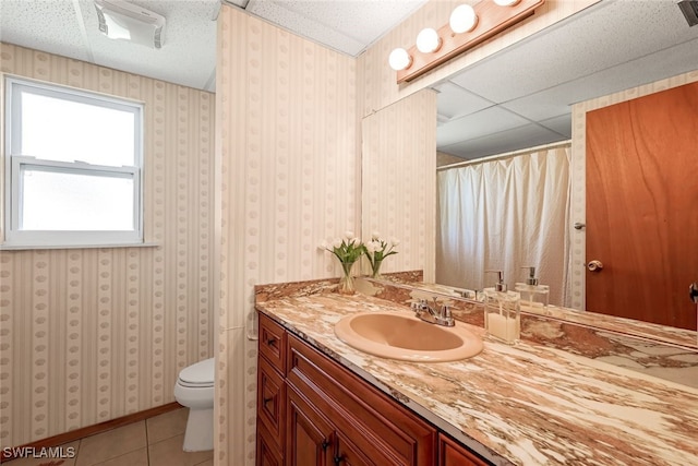 bathroom featuring toilet, vanity, tile patterned floors, and a drop ceiling