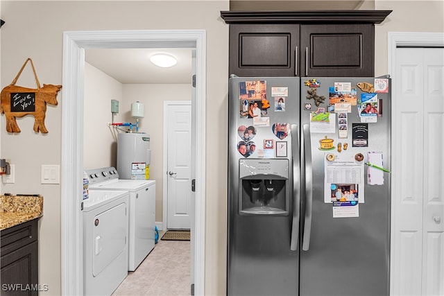 laundry room with water heater, washing machine and dryer, and light tile patterned floors