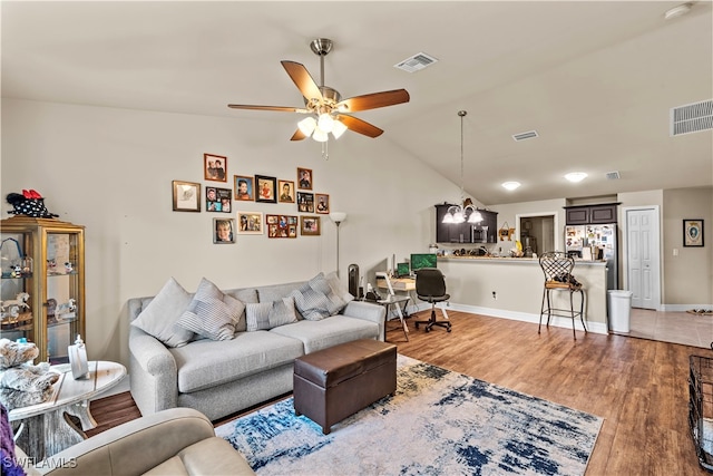 living room featuring lofted ceiling, light hardwood / wood-style flooring, and ceiling fan with notable chandelier