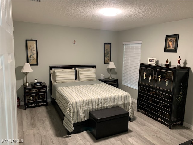 bedroom featuring light hardwood / wood-style flooring and a textured ceiling