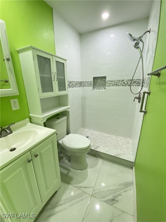 bathroom with vanity, toilet, and tiled shower