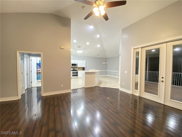 unfurnished living room featuring ceiling fan with notable chandelier, high vaulted ceiling, french doors, and dark hardwood / wood-style floors