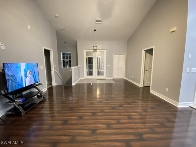 unfurnished living room featuring high vaulted ceiling and dark wood-type flooring