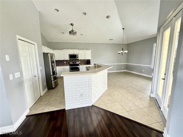 kitchen with light hardwood / wood-style floors, a notable chandelier, hanging light fixtures, white cabinets, and appliances with stainless steel finishes