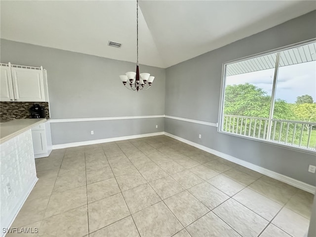 unfurnished dining area featuring light tile patterned flooring, vaulted ceiling, and a chandelier