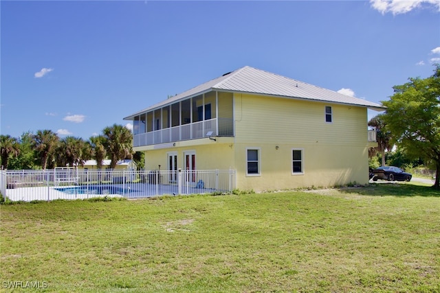 rear view of property with a yard, a sunroom, and a fenced in pool