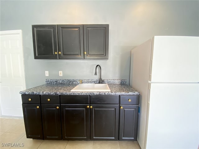 kitchen with white fridge, light tile patterned floors, and sink