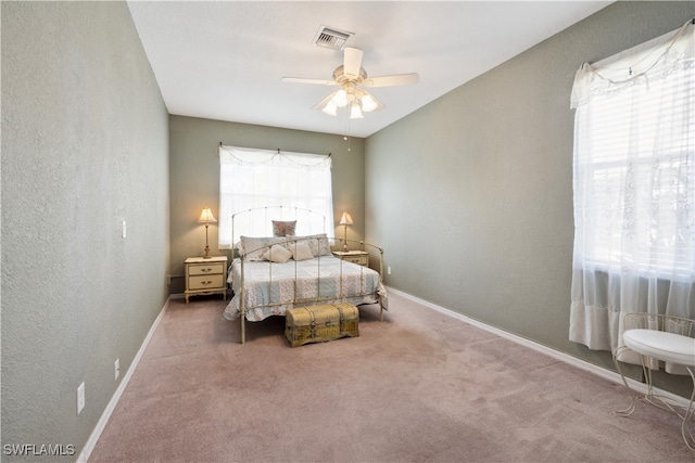 carpeted bedroom featuring multiple windows and ceiling fan