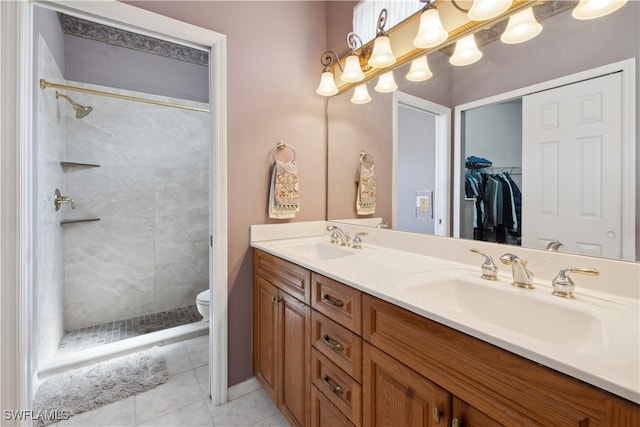 bathroom with toilet, tiled shower, tile patterned floors, and vanity