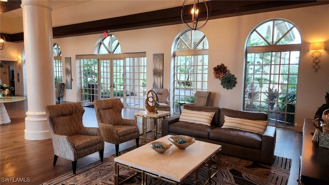 living room featuring hardwood / wood-style floors, beamed ceiling, and ornate columns